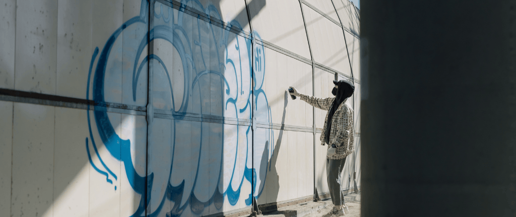 A person spray painting graffiti on a wall